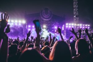 Festivalpublik framför en scen upplyst av lila strålkastare