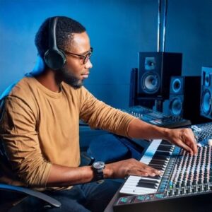 Musikproducent med hörlurar arbetar vid mixerbord och keyboard