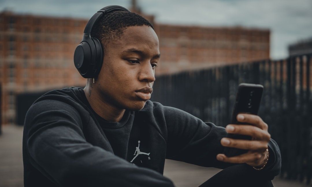 Ung person med hörlurar tittar på sin smartphone utomhus